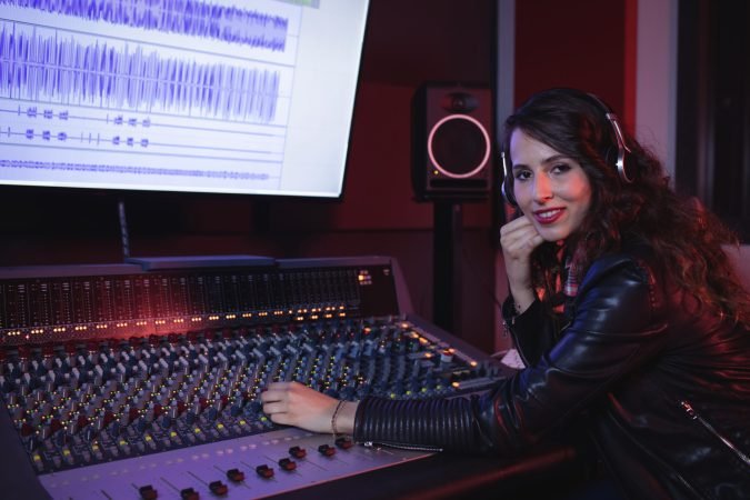 Female audio engineer using sound mixer in recording studio