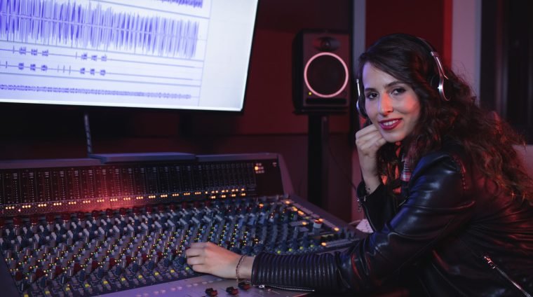 Female audio engineer using sound mixer in recording studio