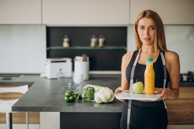 Young woman with measuting tape at the kitchen
