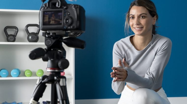 female-fitness-instructor-teaching-online-class-from-home-using-camera-tripod