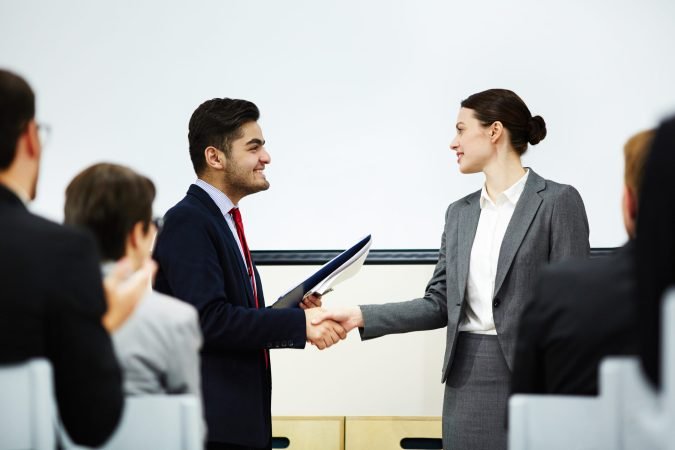 Coach congratulating one of business course attendants on graduation event